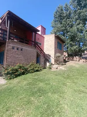 a large brick house with a grass yard at Casa Mirta in Villa Carlos Paz
