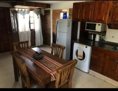 a kitchen with a wooden table and a white refrigerator at Vito in Villa Carlos Paz