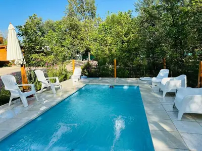 a swimming pool with chairs and an umbrella at Complejo de cabañas Munay Ki in Santa Rosa de Calamuchita