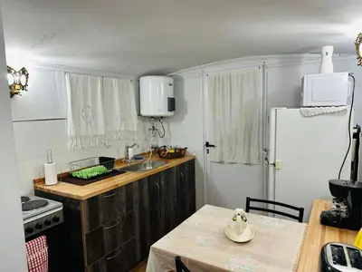 a kitchen with a table and a sink and a refrigerator at Complejo de cabañas Munay Ki in Santa Rosa de Calamuchita