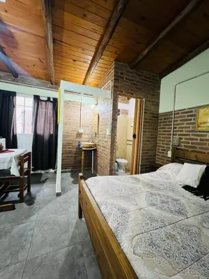 a bedroom with a large bed and a brick wall at Monoambiente in Santa Rosa de Calamuchita
