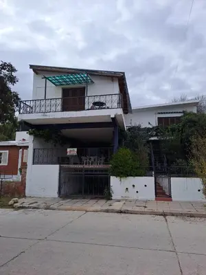 a white house with a gate in front of it at Departamentos Córdoba in Mina Clavero
