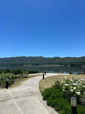 a path next to a lake with mountains in the background at Departamento en Veneto Village in Villa Parque Siquiman