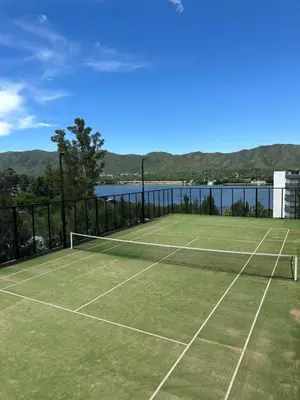 a tennis court next to a body of water at Departamento en Veneto Village in Villa Parque Siquiman