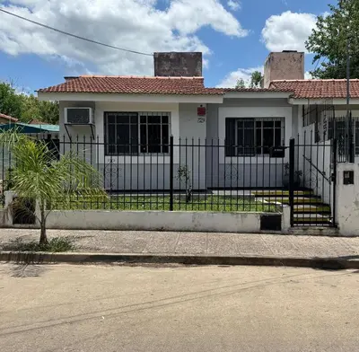 a white house with a fence in front of it at Depto 2 dormitorios, a 6 cuadras del rio y del centro in Villa Carlos Paz