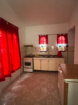 a kitchen with red curtains and a stove and sink at Depto 2 dormitorios, a 6 cuadras del rio y del centro in Villa Carlos Paz