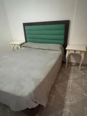 a bed with a green headboard and two tables at Depto 2 dormitorios, a 6 cuadras del rio y del centro in Villa Carlos Paz