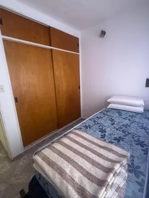 a bedroom with a bed and a wooden cabinet at Depto 2 dormitorios, a 6 cuadras del rio y del centro in Villa Carlos Paz
