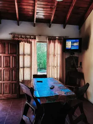 a room with a table and chairs and a television at Complejo Sol del Valle in Mina Clavero