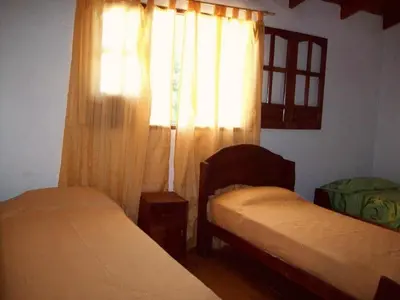 a bedroom with two beds and a window with curtains at Complejo Sol del Valle in Mina Clavero