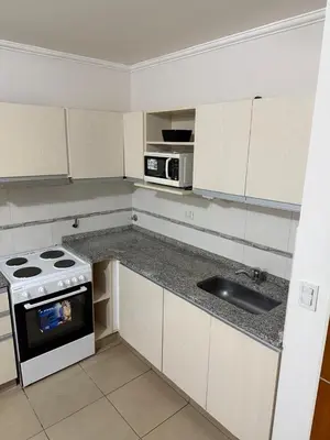 a white kitchen with a stove and a sink at Departamento Olivos IV in Villa Carlos Paz