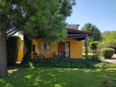 a house with a porch with chairs and a tree at Complejo Los Cuatro Elfos in La Estancia