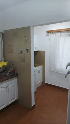 a kitchen with white cabinets and a white curtain at Villa Haus in Villa Carlos Paz