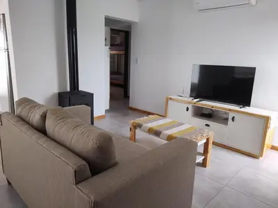 a living room with a couch and a flat screen tv at Casa Merlo San Luis Barrio privado Solares del Valle in Merlo
