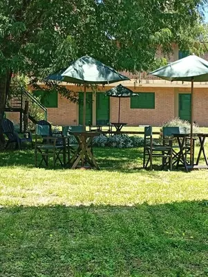 two picnic tables and umbrellas in a park at Posadas La Paz in San Antonio de Arredondo