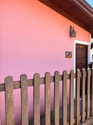 a pink wall of a house with a wooden fence at Departamento de las sierras in Embalse