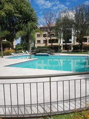 a swimming pool with a fence in front of a building at Departamento amoblado de lujo con pileta y gym in Cordoba