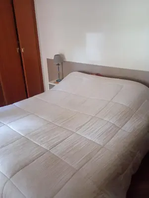 a bed in a bedroom with a white blanket on it at Departamento amoblado de lujo con pileta y gym in Cordoba