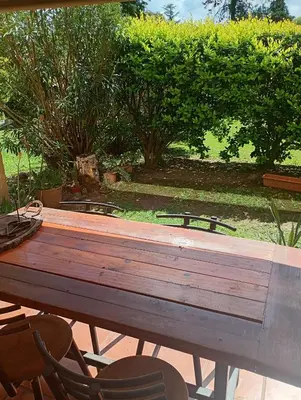 a wooden picnic table with two chairs in a garden at Departamento amoblado de lujo con pileta y gym in Cordoba