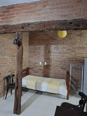 a bedroom with a bed in a brick wall at Viejo Algarrobo Villa Amancay Calamuchita in Villa Amancay
