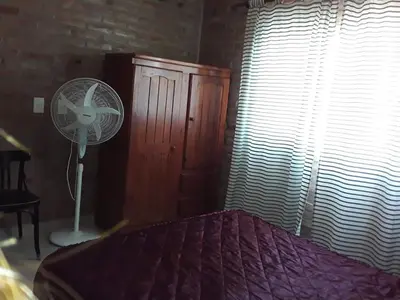a bedroom with a bed with a fan and a window at Viejo Algarrobo Villa Amancay Calamuchita in Villa Amancay