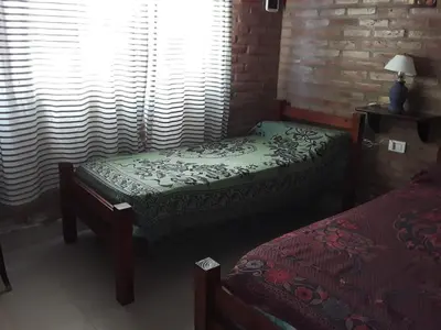 a bedroom with two twin beds and a window at Viejo Algarrobo Villa Amancay Calamuchita in Villa Amancay