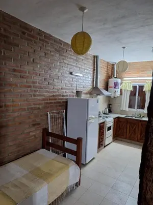 a kitchen with a white refrigerator and a brick wall at Viejo Algarrobo Villa Amancay Calamuchita in Villa Amancay
