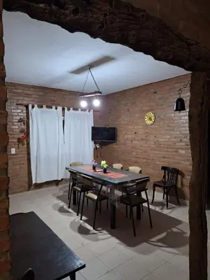 a dining room with a table and chairs and a brick wall at Viejo Algarrobo Villa Amancay Calamuchita in Villa Amancay