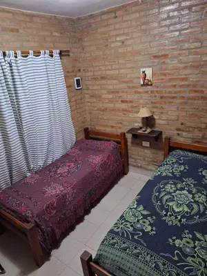 a bedroom with two beds and a table with a lamp at Viejo Algarrobo Villa Amancay Calamuchita in Villa Amancay