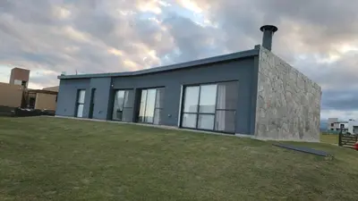 a house with a stone facade on a grass field at Casa Puerto del Águila Potrero de Garay in La Estancia