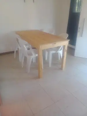 a wooden table with white chairs around it at Cabaña Mi Sol in Villa del Dique