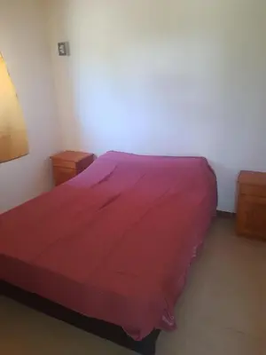a bedroom with a bed with a red bedspread at Cabaña Mi Sol in Villa del Dique