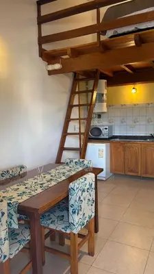 a kitchen with a wooden table and chairs and a ladder at Sol del Valle in Mina Clavero