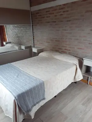 a bedroom with a bed and a brick wall at Cabañas El Mirador in Calmayo