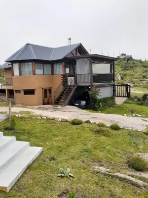 a house with a car parked in the driveway at Cabañas El Mirador in Calmayo
