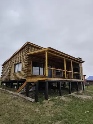 a wooden house on logs in a field at Cabaña de montaña in Villa Yacanto