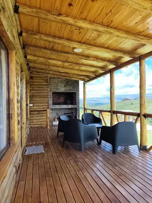 a porch with chairs and a fireplace on a deck at Cabaña de montaña in Villa Yacanto