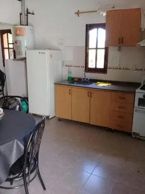 a kitchen with wooden cabinets and a white refrigerator at Marta y Chiche in Mina Clavero