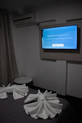 a room with a bed with towels and a tv at LakeHouse Hotel & Suites in Villa Carlos Paz