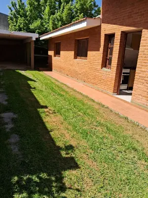 a brick building with a grassy yard in front of it at Marta y Chiche in Mina Clavero