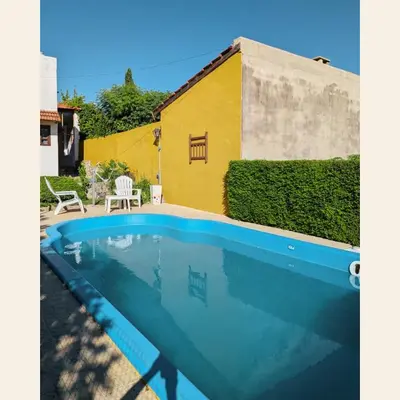 a swimming pool in front of a yellow building at Casa con pileta exclusiva Mina Clavero in Mina Clavero