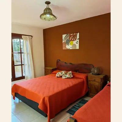 a bedroom with a bed with an orange blanket at Casa con pileta exclusiva Mina Clavero in Mina Clavero