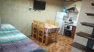 a kitchen with a table and chairs and a refrigerator at Cabañas El Molle in Cavalango
