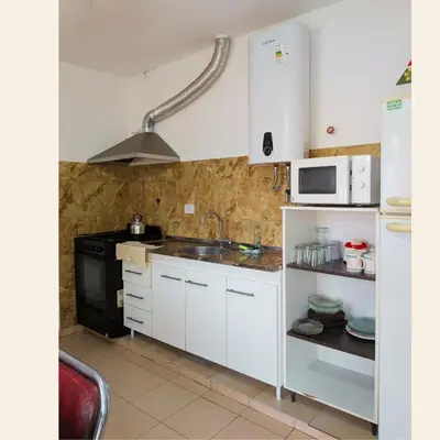 a kitchen with white cabinets and a sink and a microwave at Lo de Juany in Villa Cura Brochero