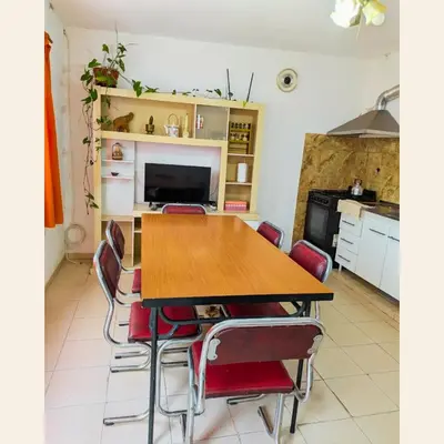 a kitchen with a wooden table and red chairs at Lo de Juany in Villa Cura Brochero