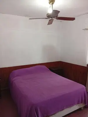 a bedroom with a purple bed and a ceiling fan at casa en Tanti in Tanti