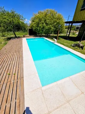a swimming pool with a wooden deck next to a house at Cabaña UMI - Un Mundo Infinito in Potrero de Garay