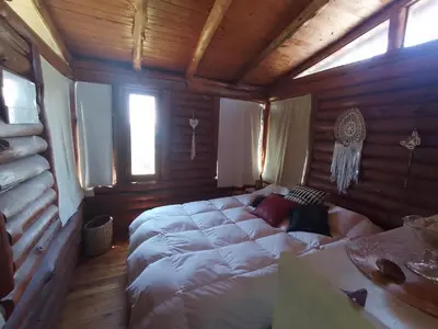 a bedroom with a large bed in a wooden room at Cabaña UMI - Un Mundo Infinito in Potrero de Garay