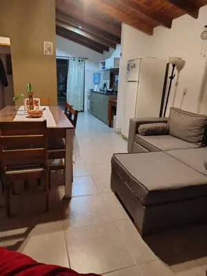 a kitchen and a living room with a table and a couch at Cabaña Quimey in Villa Rumipal