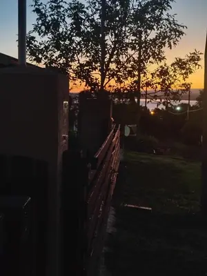 a fence with a tree and a sunset in the background at Cabaña Quimey in Villa Rumipal